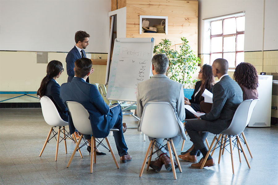 About Our Agency - Small Group Of Employees Sitting At Business Meeting In The Office